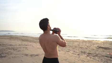 atleta entrenando en la playa con pesas rusas contra la luz de fondo