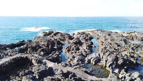 Stetiger-Schuss-Von-Blauem-Meer-Und-Wellen,-Die-Auf-Die-Vulkanische-Küste-Treffen