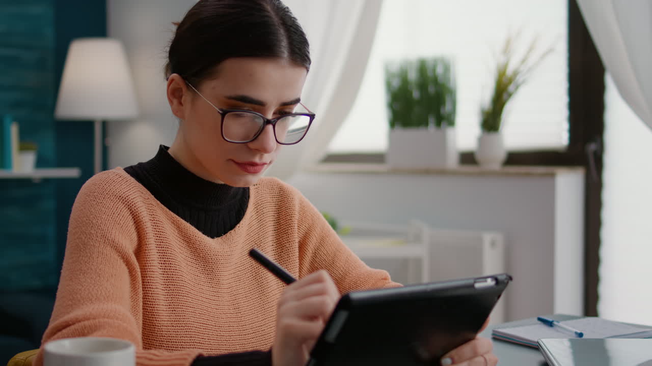 Young adult using digital tablet with stylus to do remote school work