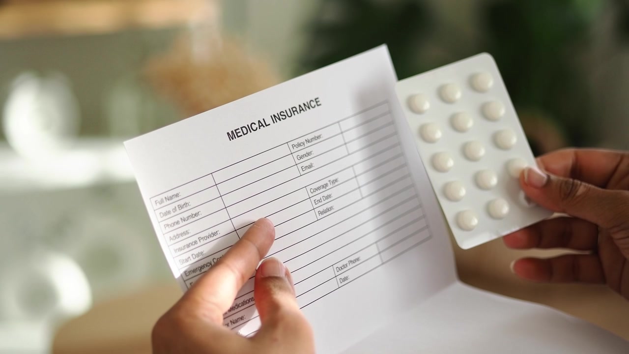Hands Holding Medical Insurance Form and Pills