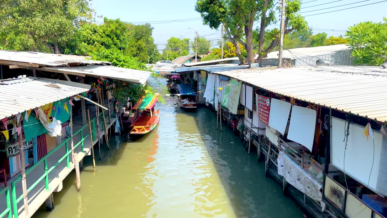 방의 khlong lat mayom 떠다니는 시장에서 활기찬 운하 장면, 밝은 낮빛 아래 보트와 시장 상점을 전시합니다.