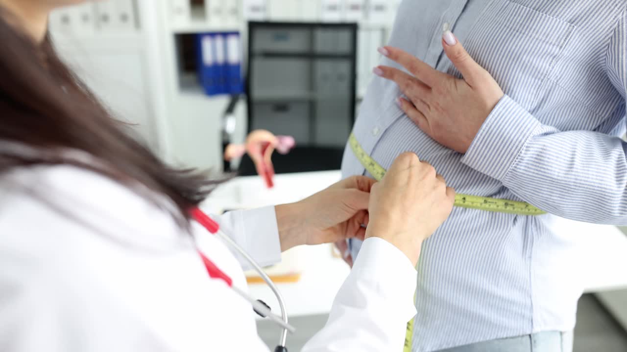 el ginecólogo mide el vientre de la mujer embarazada con centímetros