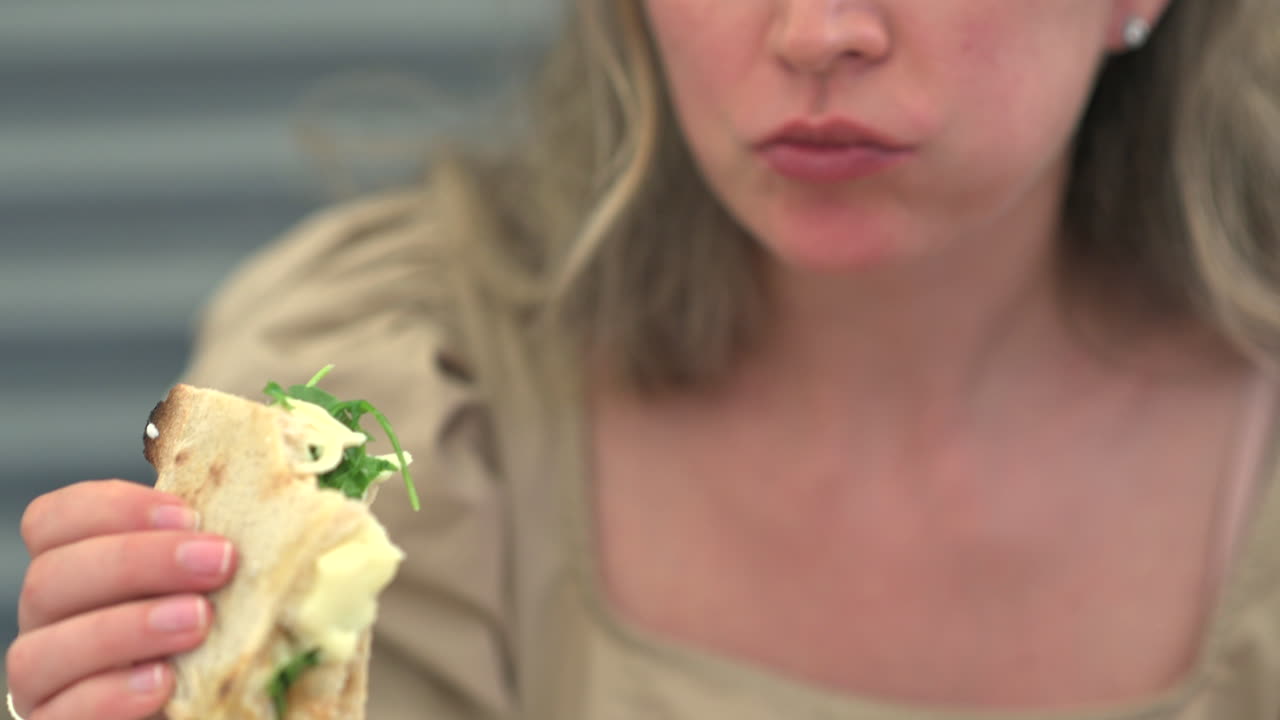 Woman eating a slice of pinsa with rucola and tomatoes at a restaurant