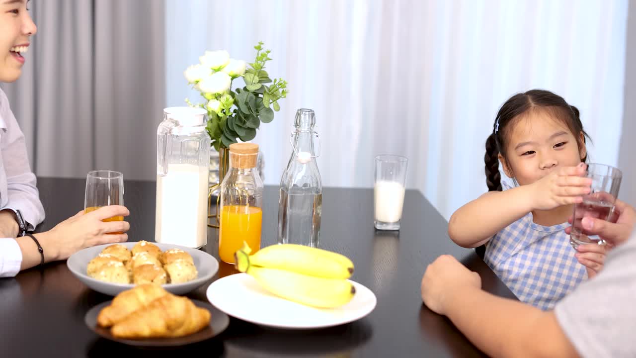 Keluarga Asia bahagia berbagi sarapan sehat di meja makan modern dengan cahaya matahari cerah