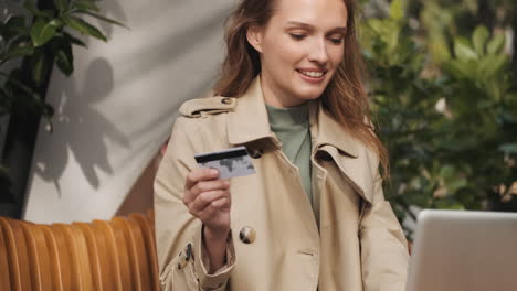 caucasian female student online shopping on laptop outdoors.