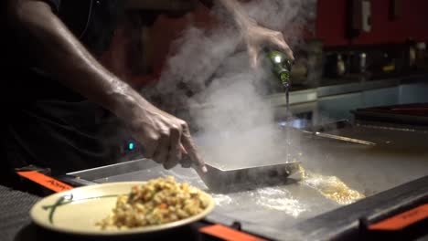 cook pouring water on stove and rice on plate