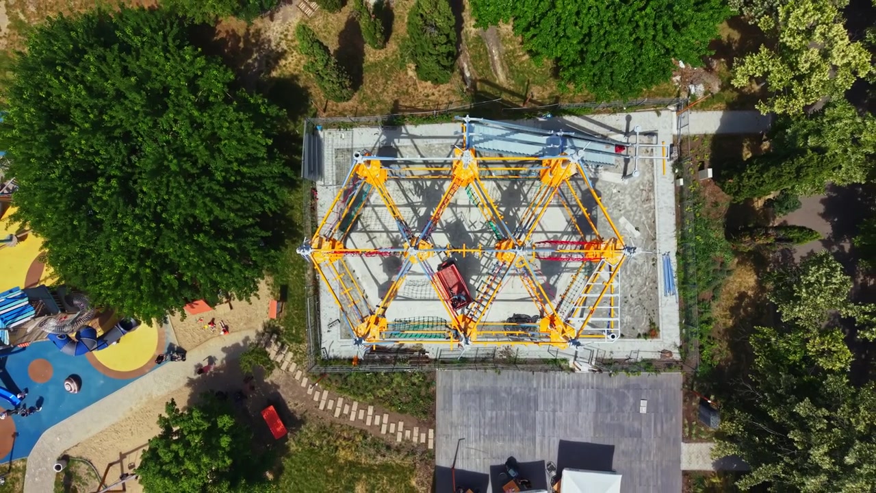 Processus de construction d'une grande structure de jeux dans un espace extérieur entouré d'arbres par une journée ensoleillée dans un parc local.