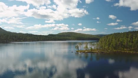 panning drone shot over a calm lake in finland with clouds reflected in it