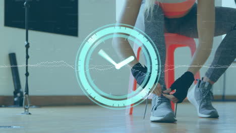 animación de reloj de neón contra la sección media de boxeador femenino atando zapatos cordones en el gimnasio