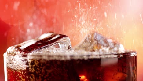 Glass-of-cola.-Ice-cola-with-splashing-bubbles-slow-motion-on-a-blurry-light-,blurry-background.