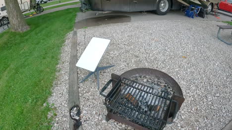 satellite antenna near a camp fire ring and rv coach in a campground