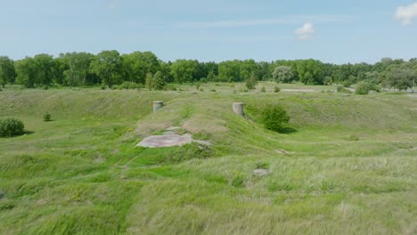 Aerial-establishing-view-of-abandoned-historical-concrete-seaside-fortification-buildings,-Southern-Forts-near-the-beach-of-Baltic-sea-in-Liepaja,-sunny-summer-day,-drone-shot-moving-forward-low