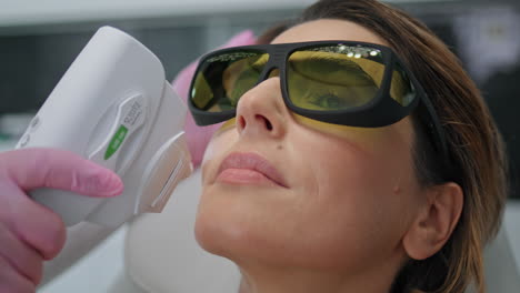 cosmetician making laser procedure to woman client in beauty salon close up.