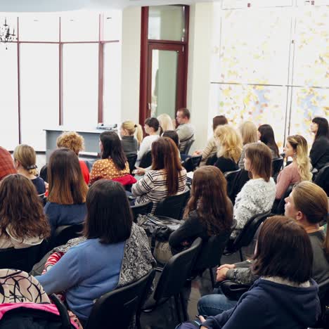 auditorium with listeners. woman conducts a lecture for young public in the modern hall. speaker talking about children.