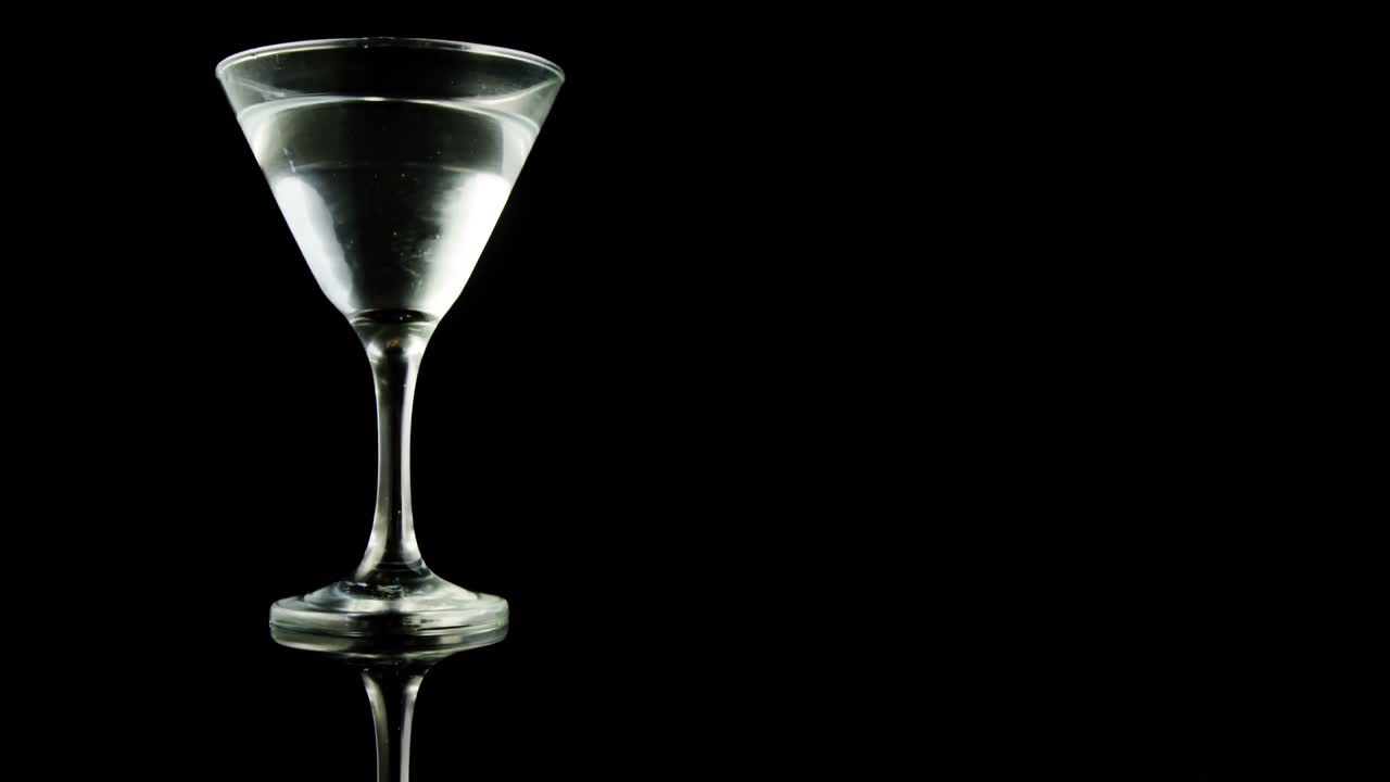 dos aceitunas verdes cayendo en el vaso de cóctel