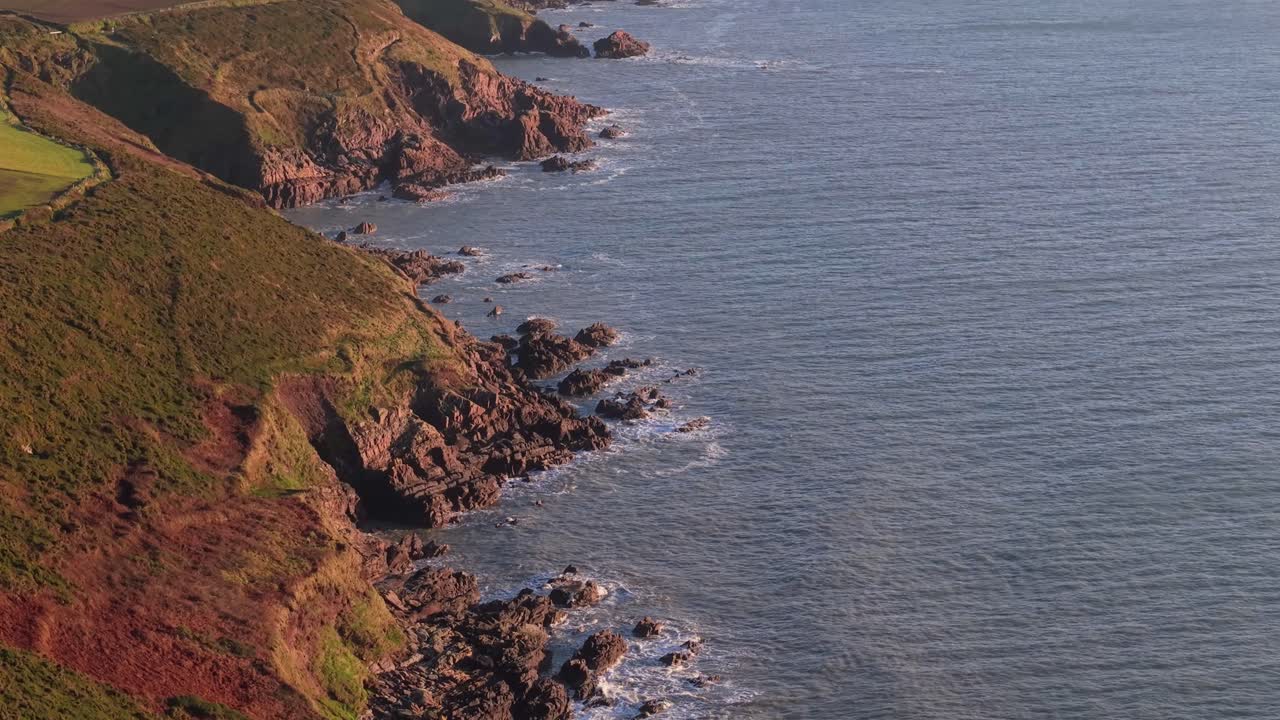 Rocky coastline of Ireland at sunrise with waves and cliffs near Ballycotton, Cork