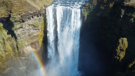 Tiro-épico-De-Retroceso-De-Una-Poderosa-Cascada-En-Islandia,-Agua-Corriendo-Por-Un-Acantilado-Alto