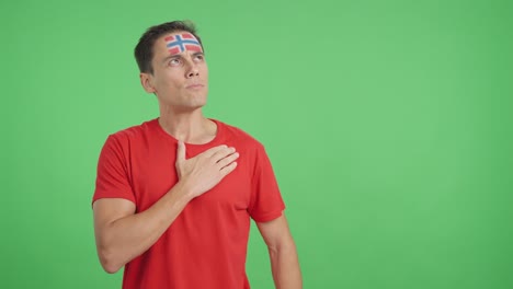 man listening to the norway national anthem with solemnity