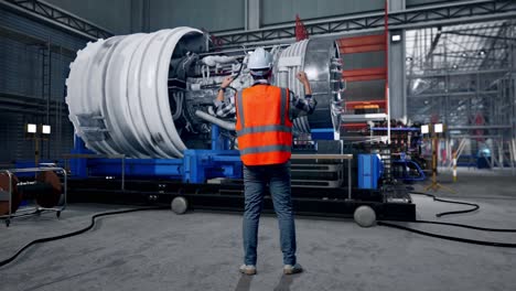 full body back view of a male engineer with safety helmet raising his hands celebrating while working with airplane engine maintenance conducted, analytics checking the turbine
