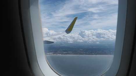 airplane window view of clouds, sky, and landscape