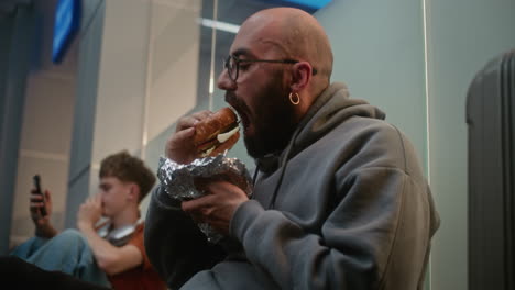man eating sandwich in airport lounge