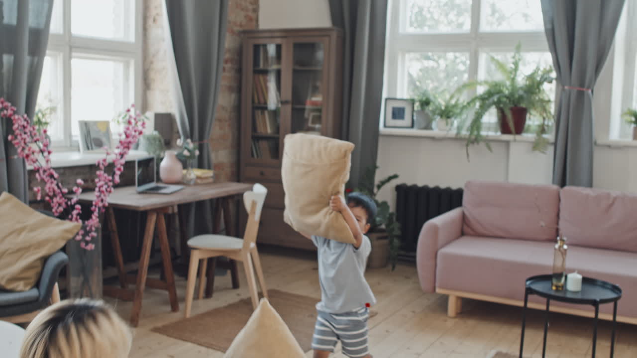 Asian Mom and Son Pillow Fighting in Living Room