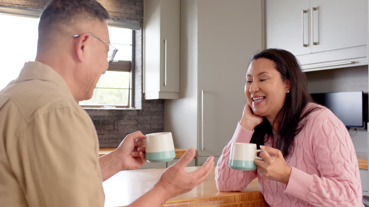 Senior asian couple enjoying coffee and conversation at home, sharing joyful moments