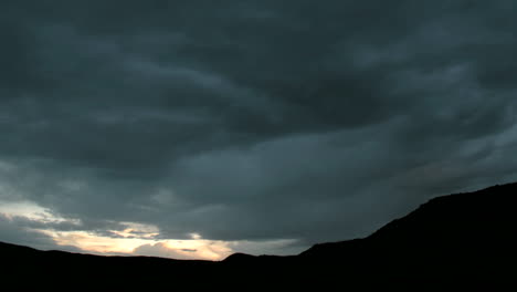 Langsames-Schwenken,-Während-Goldenes-Licht-Am-Horizont-Unter-Dunklen-Gewitterwolken-Aufflammt