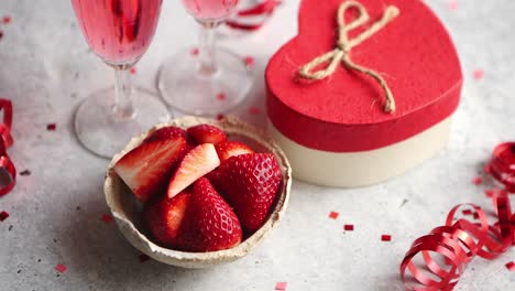 bottle of rose champagne  glasses with fresh strawberries and heart shaped gift