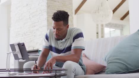 African-american-man-working-with-tablet-in-living-room