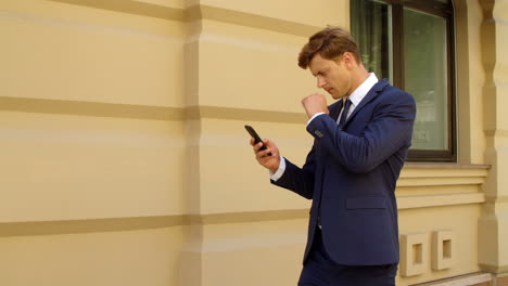 Focused-businessman-using-mobile-phone-outdoors.-Thoughtful-business-man