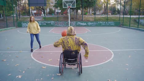 Behinderter-Basketballspieler-Im-Rollstuhl-übt-Mit-Seiner-Freundin-Auf-Dem-Offenen-Platz.