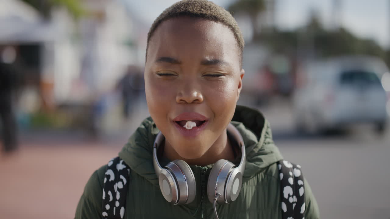 portret van vrolijke jonge afro-amerikaanse vrouw die kauwgom blaast glimlachend geniet van speels plezier op de warme zomer stedelijke strandfront