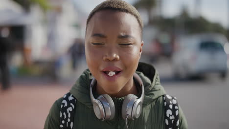 retrato de una joven afroamericana alegre soplando chicle sonriendo disfrutando de una diversión lúdica en el cálido verano frente a la playa urbana