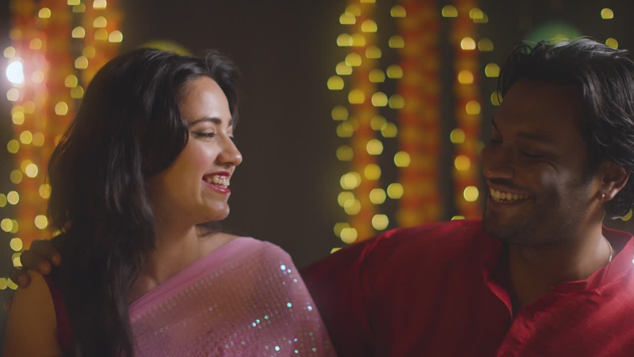 Portrait Of Smiling Asian Couple Celebrating Diwali Against Bokeh Lighting Background