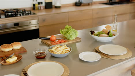preparing meal, arranging vegetables, fries, and buns on kitchen counter