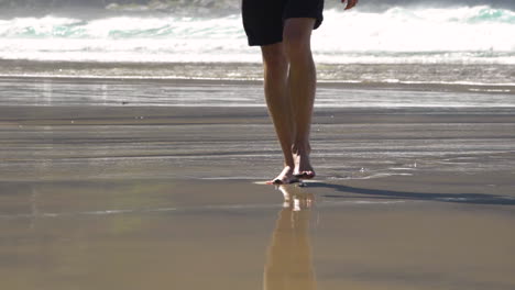 man walking in the beach in slowmotion showing bare feet stepping into sand