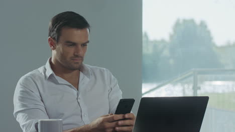 Business-man-looking-mobile-phone-at-work-place.-Concentrated-man-having-break.