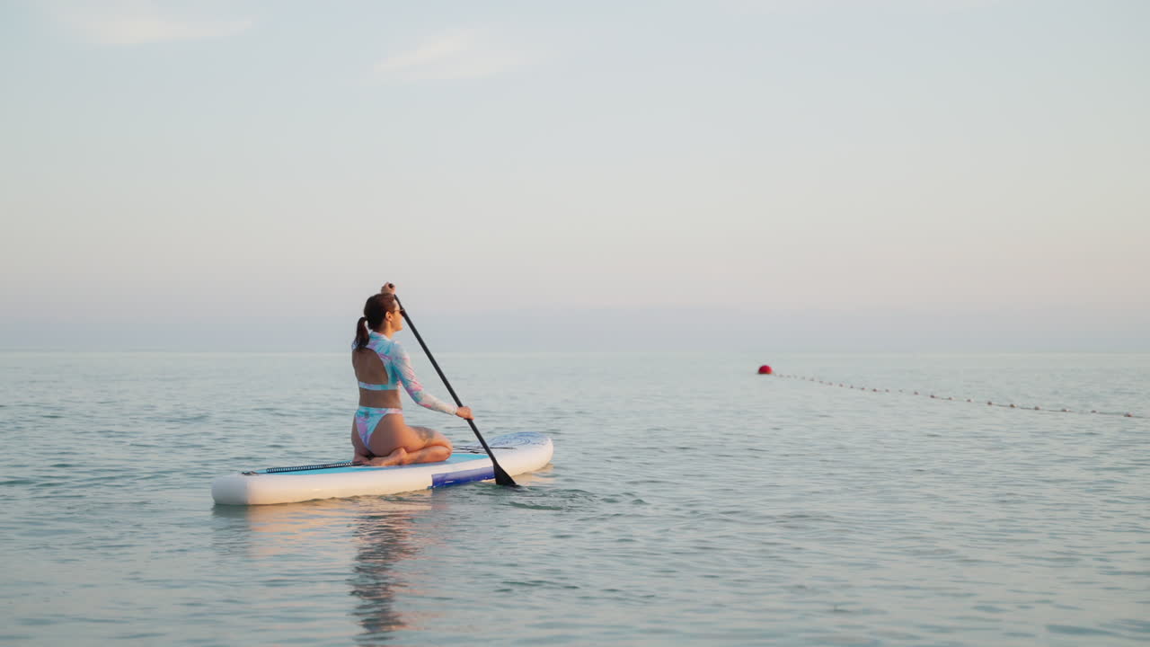 mujer haciendo paddleboard en el océano al atardecer