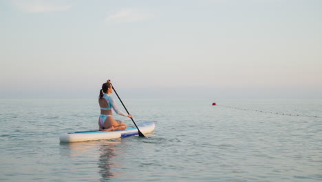 woman paddleboarding in the ocean at sunset