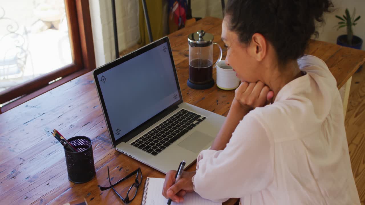 mujer caucásica usando computadora portátil y escribiendo, trabajando desde casa