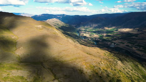 Small-town-in-deep-valley-of-New-Zealand-mountain-ranges,-aerial-drone-view