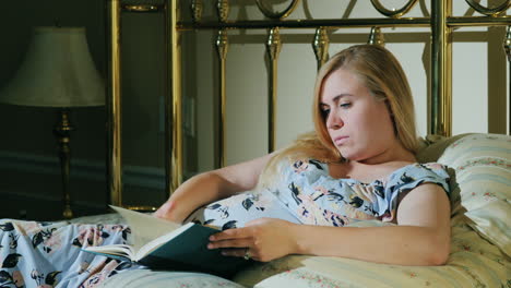 pregnant woman reads a book in her bed