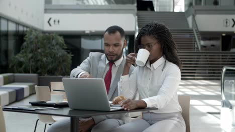 Slow-motion-shot-of-two-colleagues-with-laptop-sitting-at-cafe