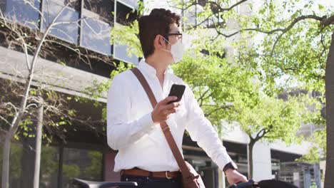 Hombre-Asiático-Con-Mascarilla-Y-Bicicleta-Usando-Un-Teléfono-Inteligente-En-La-Calle