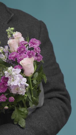 Vertical-Shot-of-a-Man-Holding-Out-Flowers