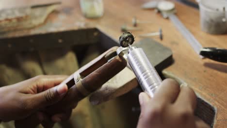 biracial female worker shaping ring using handcraft tools in workshop in slow motion