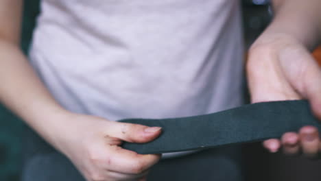 person cleans black leather fabric strip in hands closeup