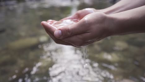 la mano agarrando el agua del arroyo. movimiento lento.