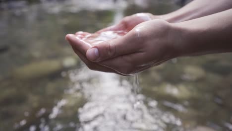 the hand grabbing the water from the stream. slow motion.